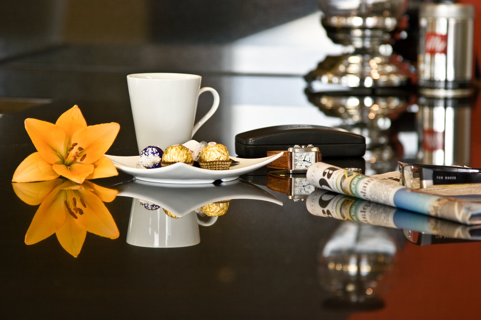 Stillebend mit Kaffeetasse, Zeitung, Blume und verschiedene Arrangement auf einer spiegelnden Oberfläche