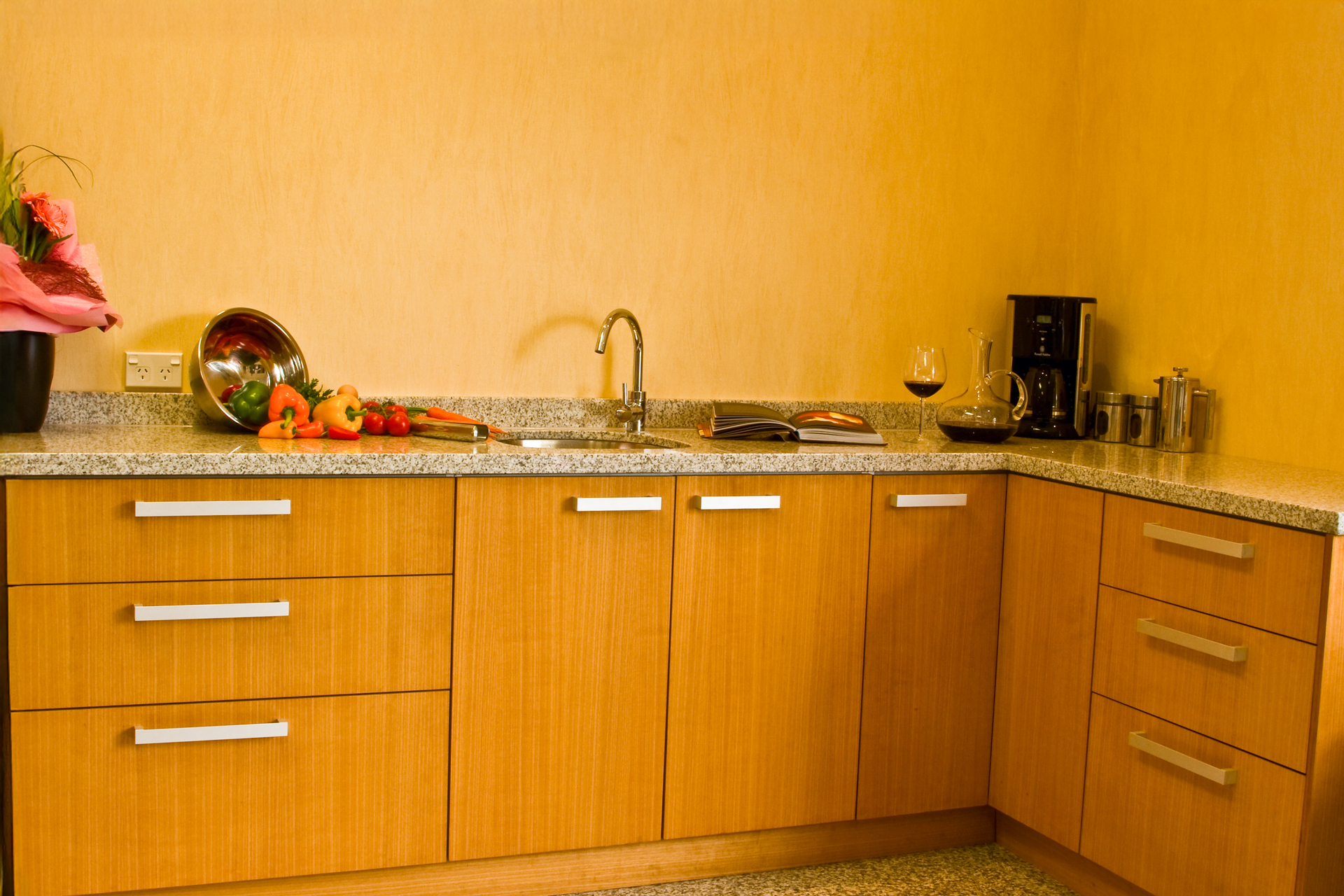 Küchenzeile in orangenen Holz mit grauer Marmorplatte